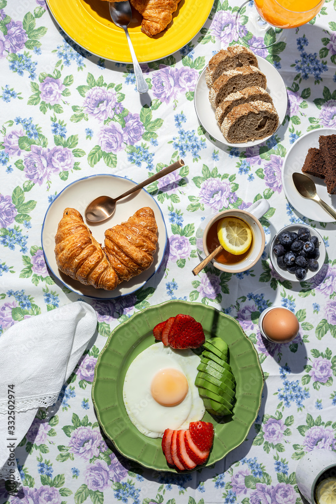 Homemade full healthy breakfast in sunlight with eggs, avocado, strawberries, blueberries, sponge cake, croissants, toast, tea, coffee and orange juice Homemade full healthy breakfast in sunlight with eggs, avocado, strawberries, blueberries, sponge cake, croissants, toast, tea, coffee and orange juice