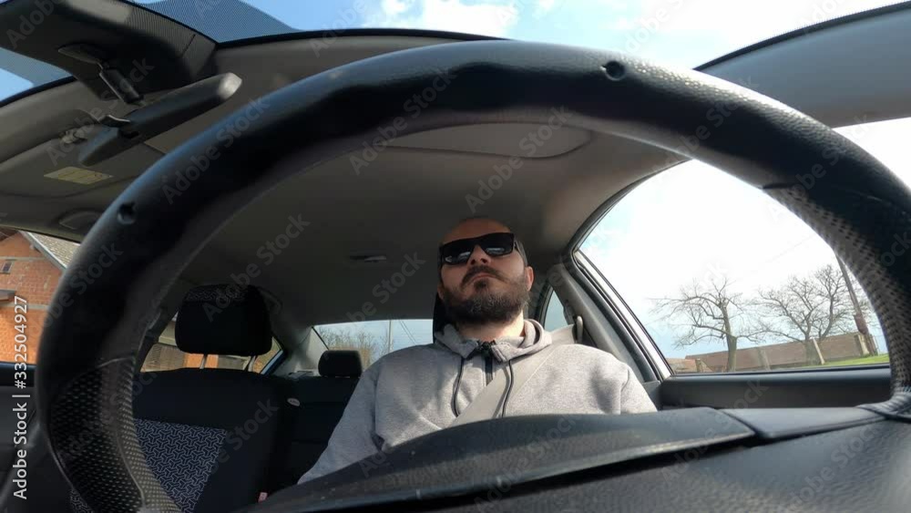 Man with sunglasses driving a car, wide angle view through the steering wheel
Man with sunglasses driving a car, wide angle view through the steering wheel