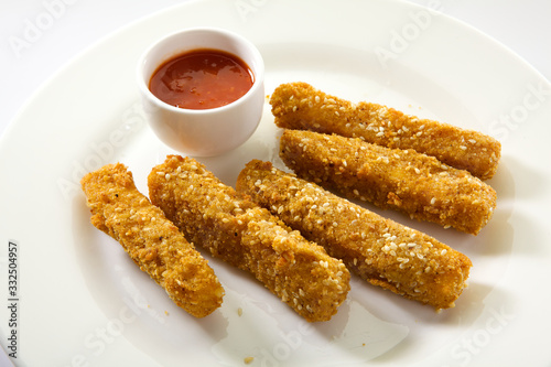 Crispy fried mozzarella sticks served with spicy marinara dipping sauce. Appetizing Fried Mozzarella Sticks isolated on white background