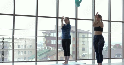 girls practice yoga in a large, light room. coach and student. sport training concept.