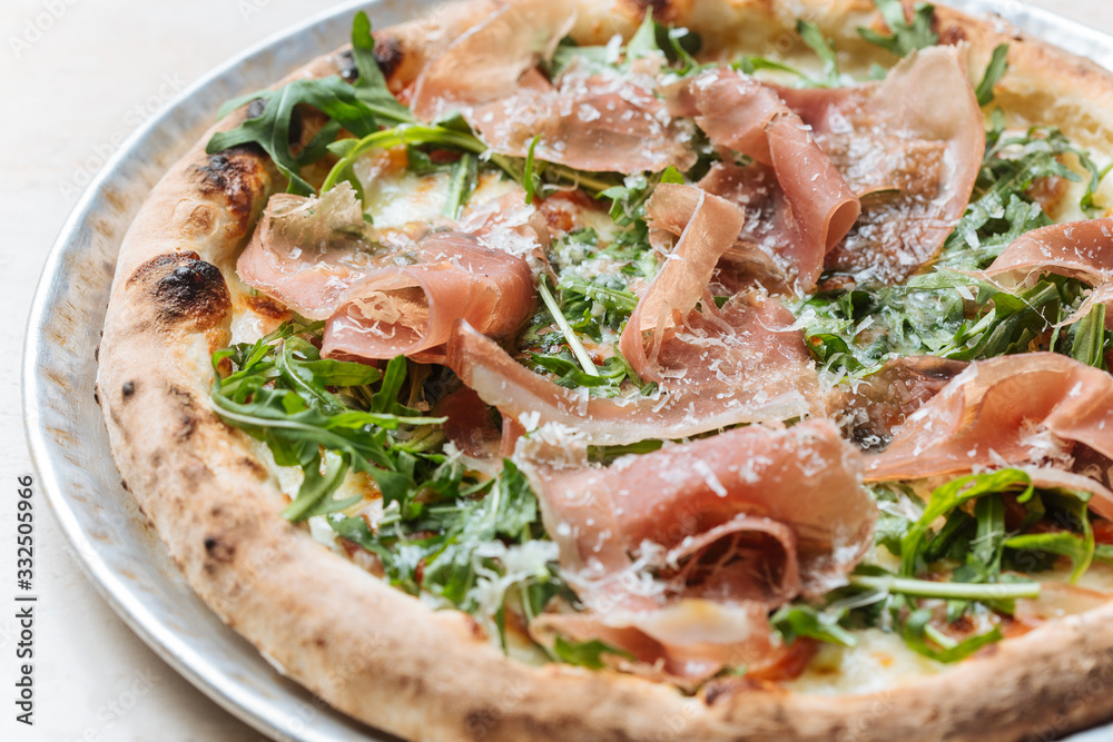 Top view of tasty pizza with thin slices of bacon and fresh greenery on plate in restaurant Top view of tasty pizza with thin slices of bacon and fresh greenery on plate in restaurant