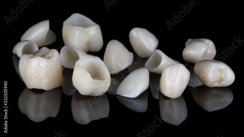 high-quality dental crowns for total prosthetics of the patient on a black background with reflection