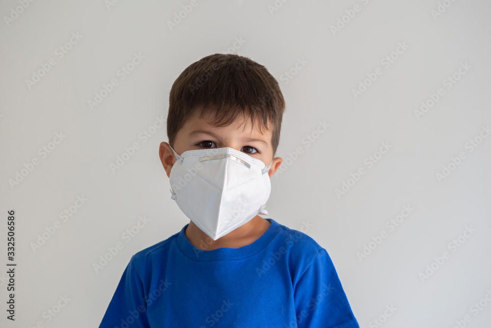 Closeup of caucasian boy wearing surgical mask. Face mask for protection against coronavirus outbreaks. Concept of protection against biological threat. Social isolation to prevent respiratory disease Closeup of caucasian boy wearing surgical mask. Face mask for protection against coronavirus outbreaks. Concept of protection against biological threat. Social isolation to prevent respiratory disease