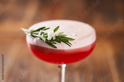 From above of stylish glass with alcohol red cocktail consist of gin egg whites lime juice and raspberry syrup decorated with rosemary  photo