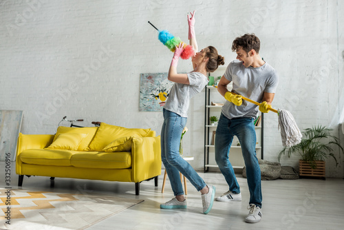 Fotografie man and woman with household singing while doing spring cleaning in living room