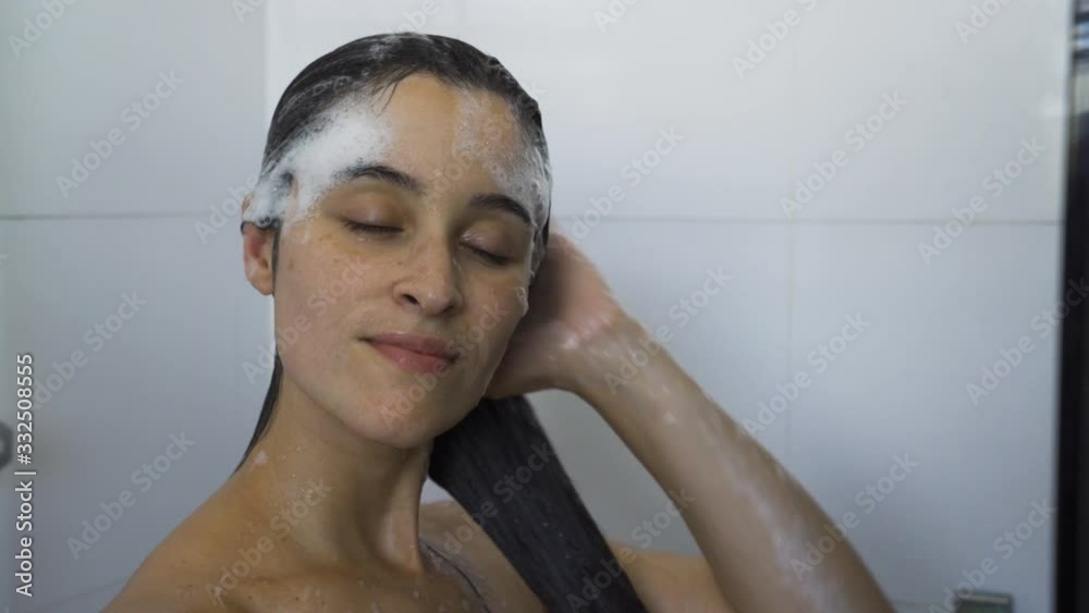 Young woman washes away the shampoo from her hair Young woman washes away the shampoo from her hair