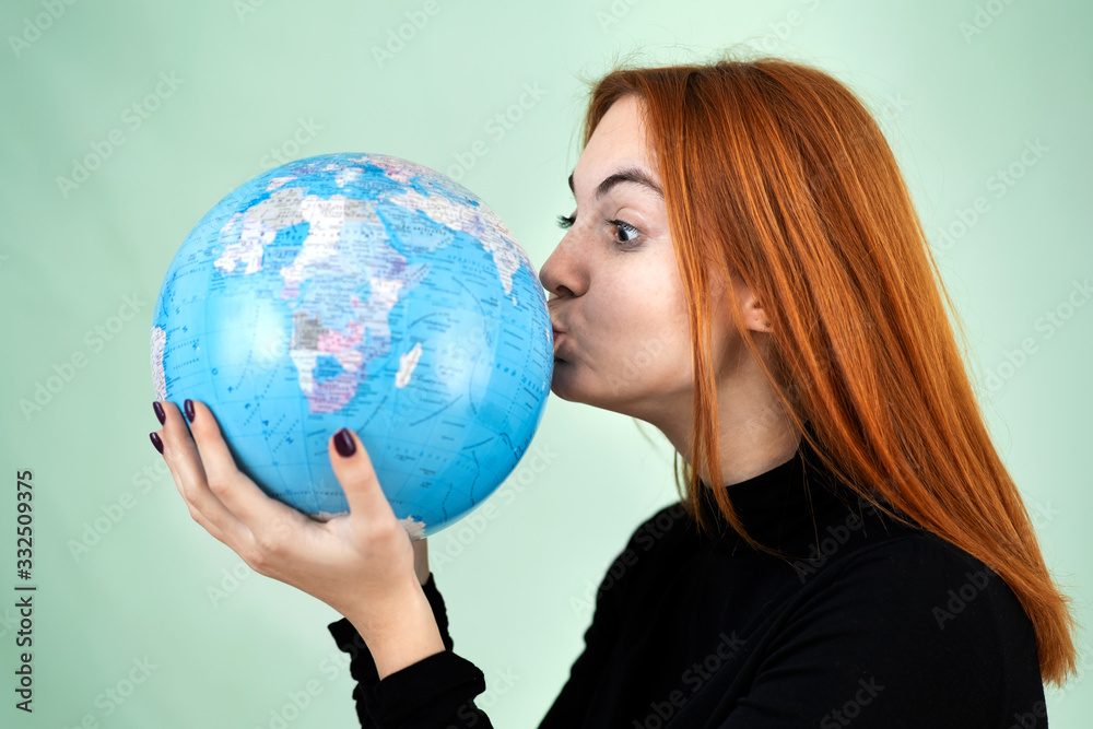 Portrait of a happy young woman holding geographic globe of the world in her hands. Travel destination and planet protection concept. Portrait of a happy young woman holding geographic globe of the world in her hands. Travel destination and planet protection concept.