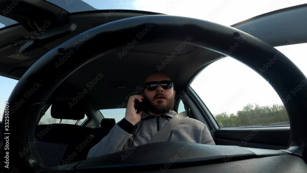 Man with sunglasses driving a car, wide angle view through the steering wheel, talking on phone
Man with sunglasses driving a car, wide angle view through the steering wheel, talking on phone