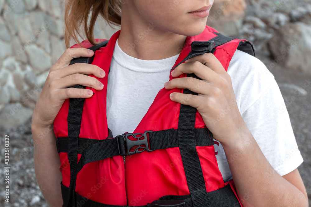 Φωτογραφία Caucasian female in red life jacket stand in seashore and looks at the sea