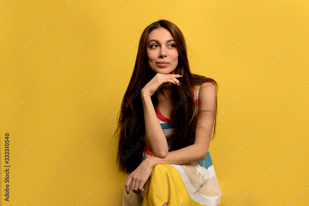Incredible dreaming girl with long hair wearing summer dress posing over yellow background Incredible dreaming girl with long hair wearing summer dress posing over yellow background