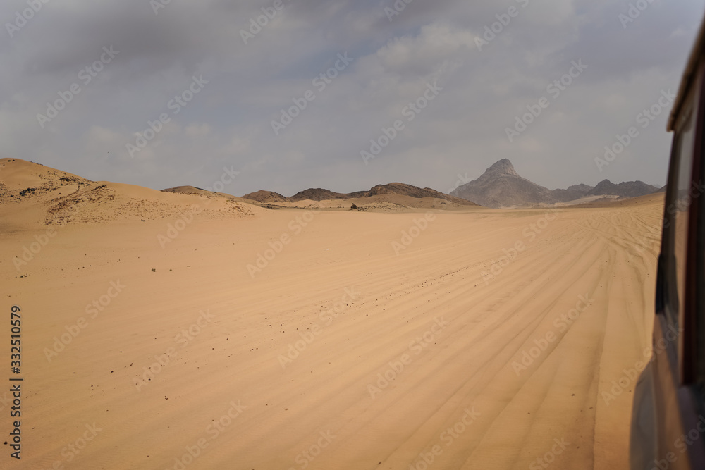 Scenic landscape of sun rays through clouds in desert from car window in Saudi Arabia Scenic landscape of sun rays through clouds in desert from car window in Saudi Arabia