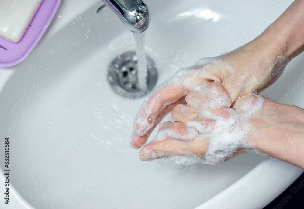 Woman washing hands with soap under the faucet in bathroom. Step by step picture instructions for thorough medical procedure. Step 7, wash the right thumb. Woman washing hands with soap under the faucet in bathroom. Step by step picture instructions for thorough medical procedure. Step 7, wash the right thumb.