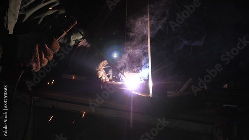 bright light and sparks from welding. Industrial worker in a protective mask using modern welding machine for welding metal structures in industrial production at a metal processing plant.