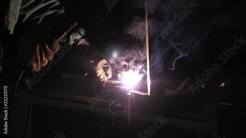 bright light and sparks from welding. Industrial worker in a protective mask using modern welding machine for welding metal structures in industrial production at a metal processing plant.