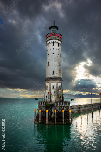 Lighthouse in port of Lindau town by the bodensee lake in Germany with dark clouds and Alp mountains in the background