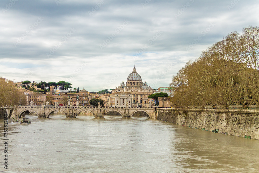 View of the Tiber river with bridge and St Peter´s Basilica in the background on a rainy autumn day, Rome, Italy.