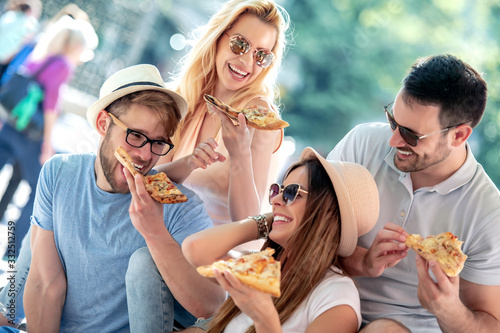 Group of young people in the park eating pizza.