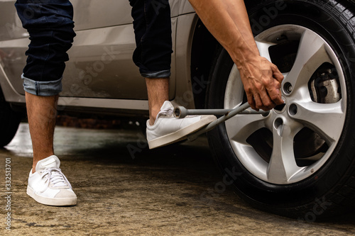  Topic of problems with the car on the road. man using force to loosen bolts on car wheel. roadside assistance concept