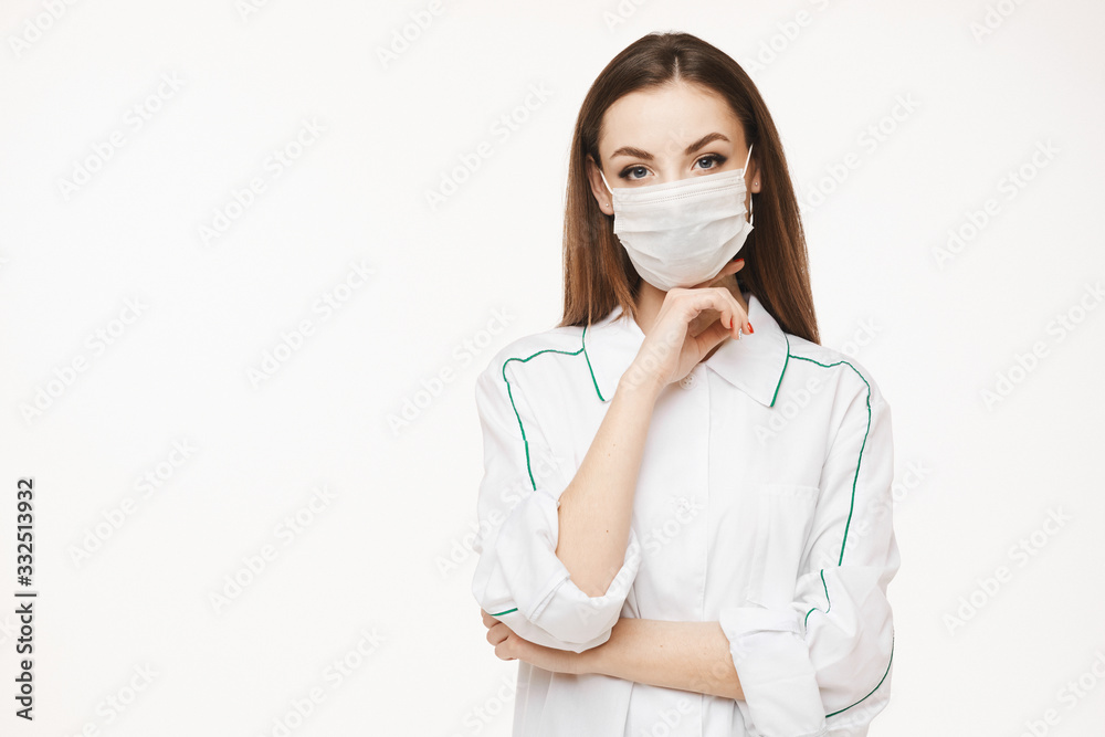 Beautiful female doctor or nurse wearing protective mask and medical gown posing on white background with copy space, isolated. Young woman in medical uniform. Healthcare concept Beautiful female doctor or nurse wearing protective mask and medical gown posing on white background with copy space, isolated. Young woman in medical uniform. Healthcare concept