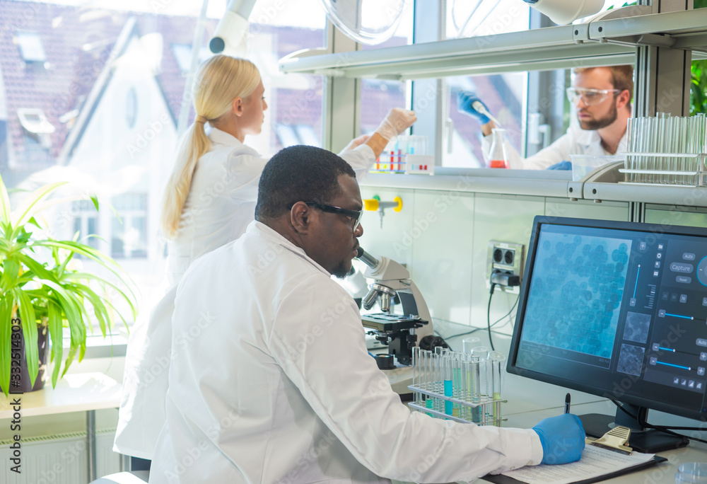 Scientist and students working in lab. Doctor teaching interns to make blood analyzing research. Coronavirus, chemistry, bacteriology, virology and health care Scientist and students working in lab. Doctor teaching interns to make blood analyzing research. Coronavirus, chemistry, bacteriology, virology and health care