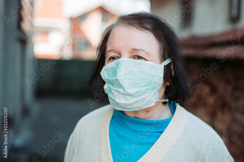 Outdoor photo of elderly woman wearing protective, surgical mask.