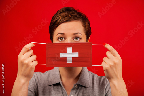Coronavirus COVID-19 in Switzerland. Woman in medical protective mask with the image of the flag of Switzerland.