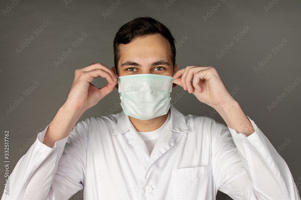 The doctor holds and puts on a medical mask to protect himself from a new virus - the coronavirus The doctor holds and puts on a medical mask to protect himself from a new virus - the coronavirus