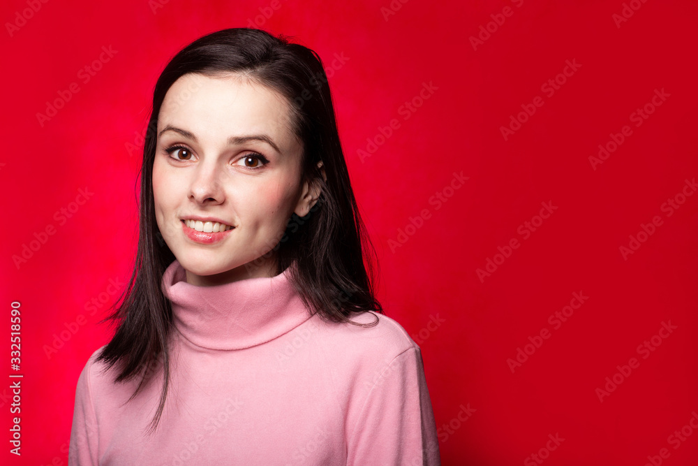 beautiful girl in a pink turtleneck talking on the phone on a red background