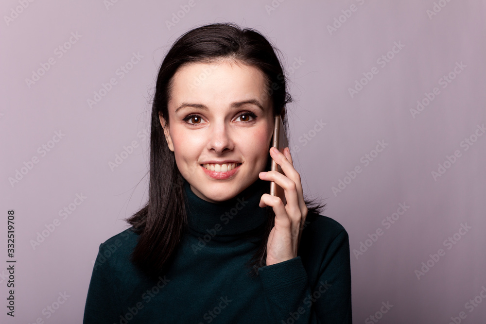 girl in a green turtleneck talking on the phone, portrait on a gray background girl in a green turtleneck talking on the phone, portrait on a gray background