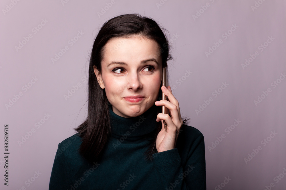girl in a green turtleneck talking on the phone, portrait on a gray background girl in a green turtleneck talking on the phone, portrait on a gray background