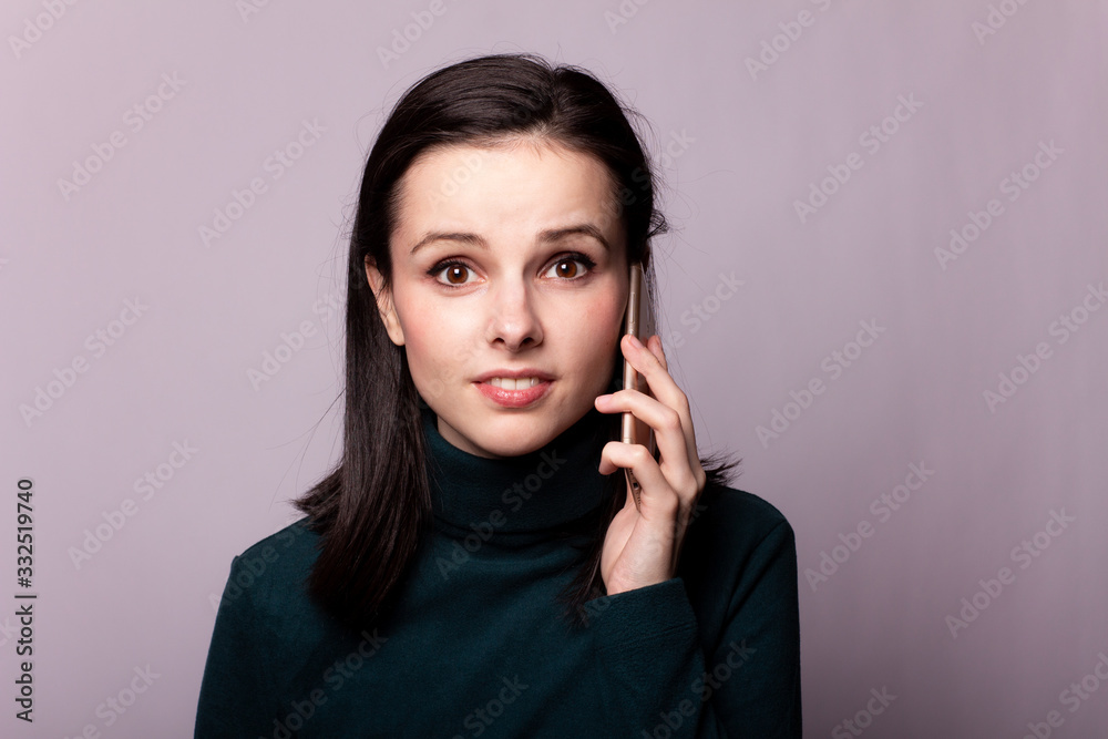 girl in a green turtleneck talking on the phone, portrait on a gray background girl in a green turtleneck talking on the phone, portrait on a gray background