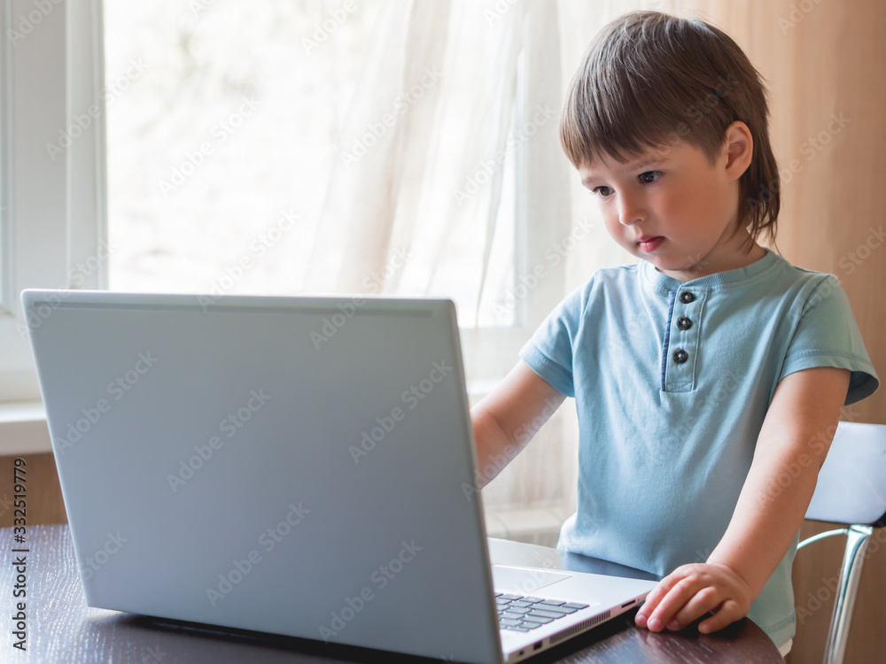 Curious toddler boy explores the laptop and presses buttons on computer keyboard. Curious toddler boy explores the laptop and presses buttons on computer keyboard.