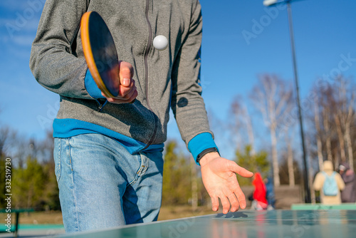 guy plays table tennis pingpong on the street. racket and ball with a tennis green table. hands in the frame and racket.