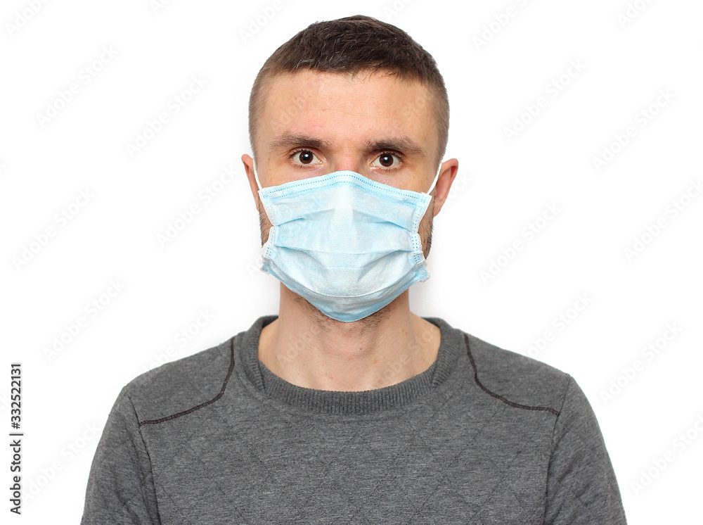 Portrait of brunette man in a surgical bandage on a white background, coronavirus, illness, infection, quarantine, medical mask Portrait of brunette man in a surgical bandage on a white background, coronavirus, illness, infection, quarantine, medical mask