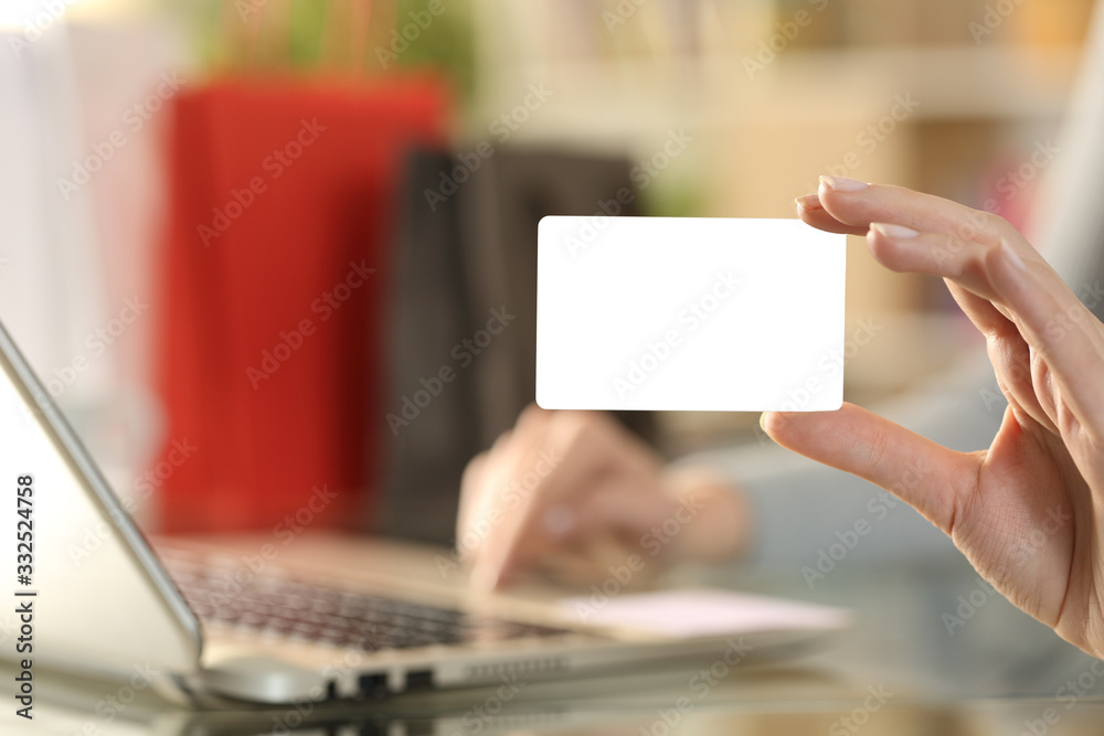 Shopper hand showing blank credit card paying on laptop Shopper hand showing blank credit card paying on laptop