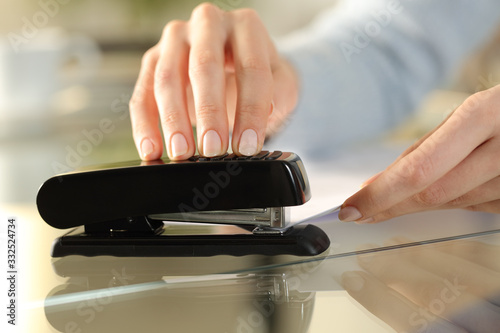Girl hands using stapler on documents over a desk at home