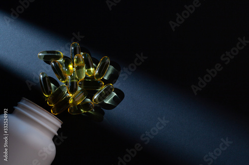 Omega-3 vitamins, fatty acids. Fish oil in yellow capsules on a black background.