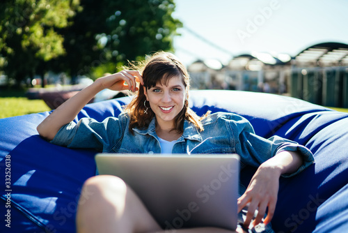 Glad charming lady using computer chilling in park