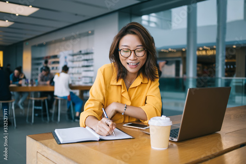 Canvas Print Happy freelancer working on laptop and taking notes