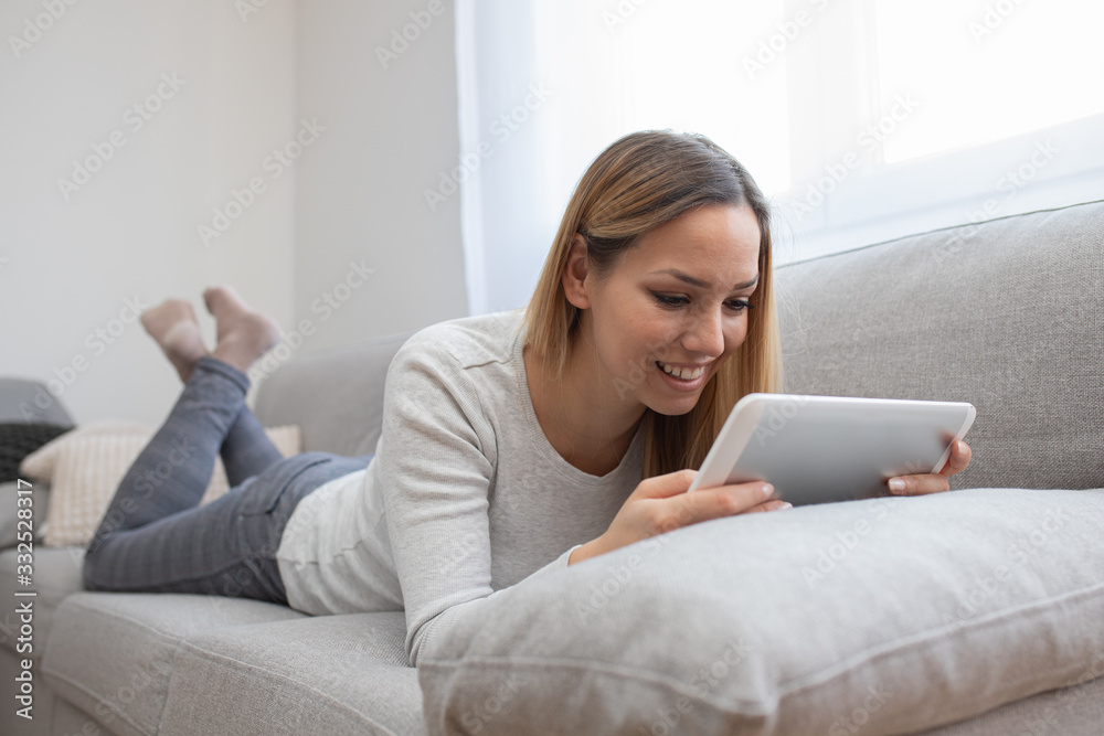 Woman using tablet on a home couch. Woman surfing on line or working from home concept