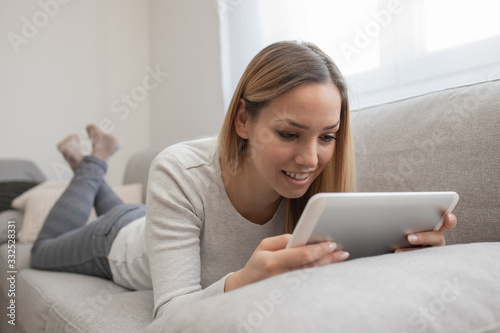 Woman using tablet on a home couch. Woman surfing on line or working from home concept