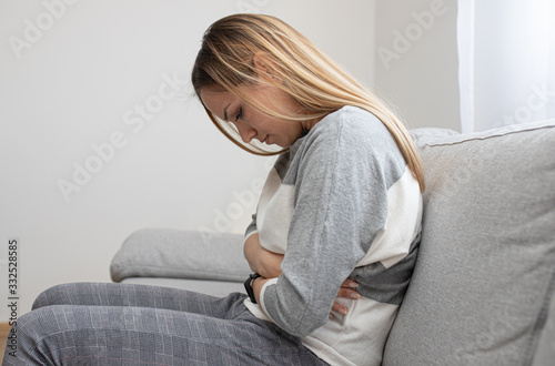 Girl with stomach ache sitting on sofa