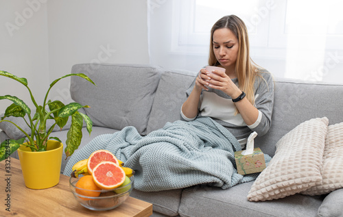 Wallpaper Mural Sick woman sitting under the blanket. Sick woman with seasonal infections, flu, allergy lying in bed. Sick woman covered with a blanket lying in bed with high fever and a flu, resting and drinking tea Torontodigital.ca