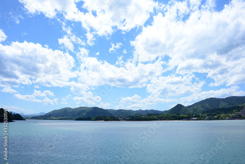 Vista de tierra desde el mar con un gran cielo azul lleno de nubes blancas