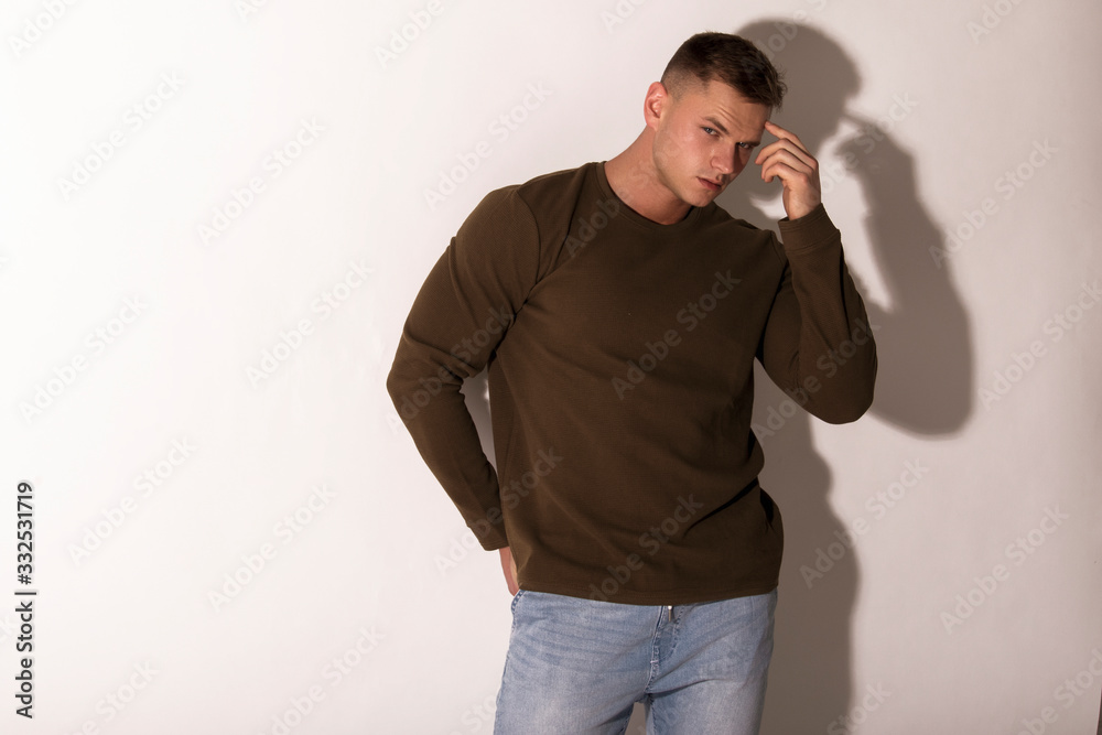 Muscle strong beautiful stripped male model in denim jeans with jumiper jumper on white isolated font background with shadow Muscle strong beautiful stripped male model in denim jeans with jumiper jumper on white isolated font background with shadow