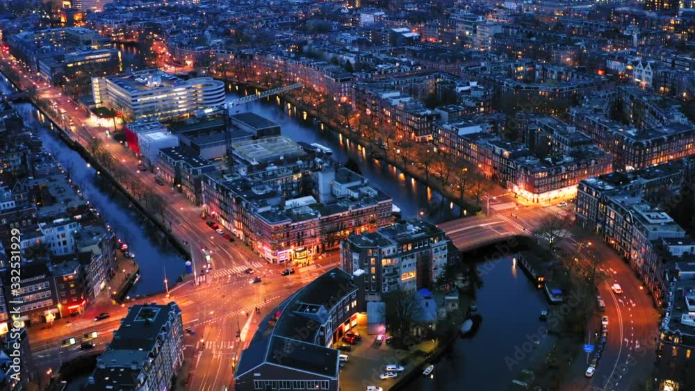 Beautiful night aerial view of Amsterdam downtown from above with many narrow canals, illuminated streets and old historic houses, drone footage
