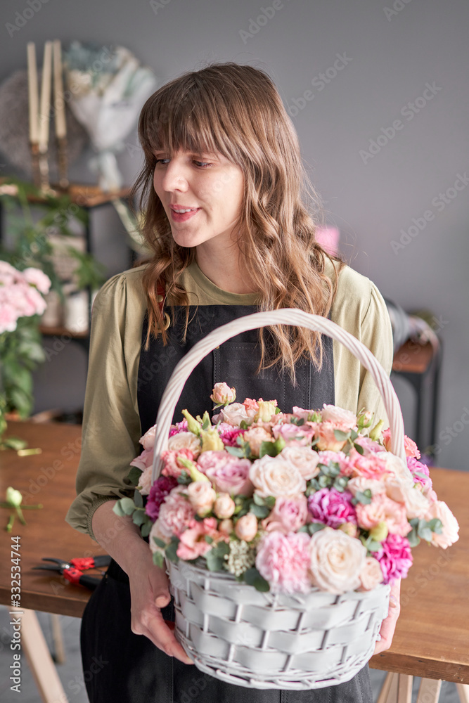 Fototapeta premium Small flower shop and Flowers delivery. Flower arrangement in Wicker basket. Beautiful bouquet of mixed flowers in woman hand. Handsome fresh bouquet.