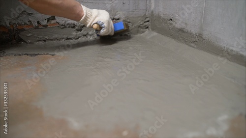 Waterproofing coating. Cover the concrete wall with a cement-polymer waterproofing membrane. Worker waterproofing with a brush