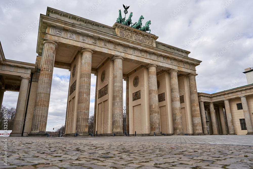 View on the famous Brandenburg gate on the Pariser square during the dusk in Berlin city, parisian square without tourists and visitors - deserted, sunset with blue sky and small clouds View on the famous Brandenburg gate on the Pariser square during the dusk in Berlin city, parisian square without tourists and visitors - deserted, sunset with blue sky and small clouds