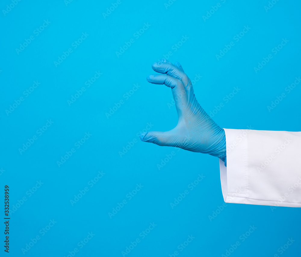 doctor’s hand is wearing a blue sterile rubber glove holding an object, blue background doctor’s hand is wearing a blue sterile rubber glove holding an object, blue background